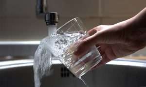 glass with water flowing from a tap