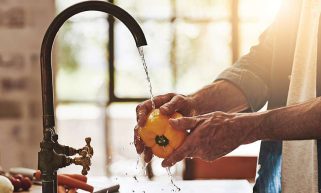 Man washing vegetables using water from tap