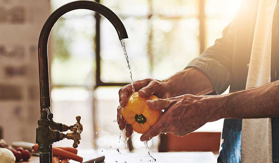 Man washing vegetables using water from tap